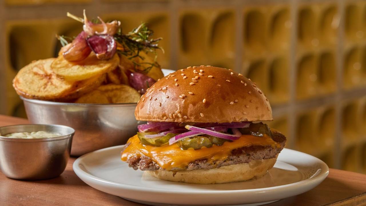 Hambúrguer em prato branco com batata atrás