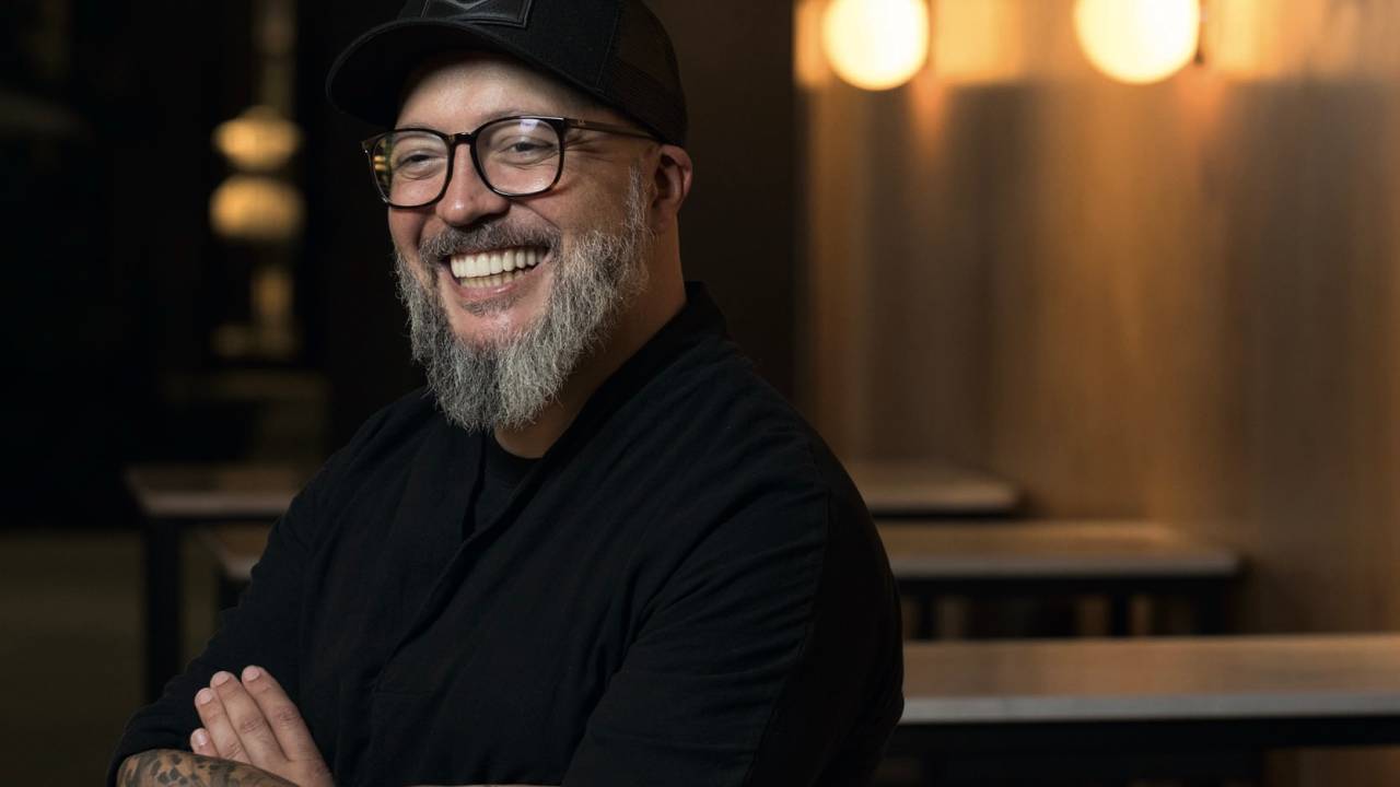 Homem sorrindo de óculos e boné