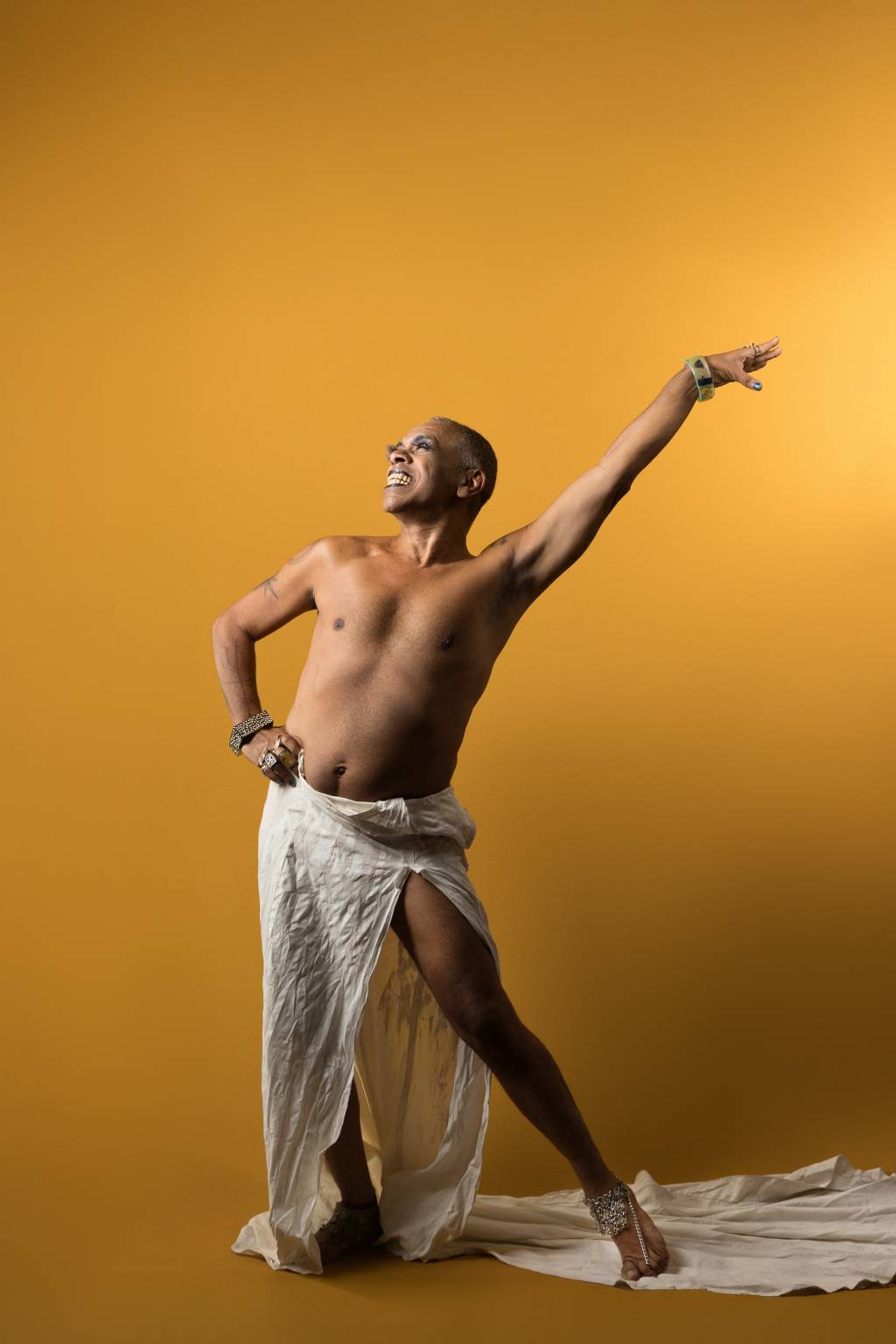 Márcio Januário Em pose imponente, com um braço para cima, Márcio posa sem camisa em frente a fundo amarelo