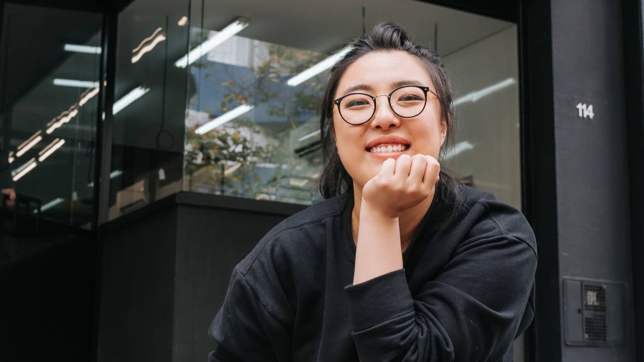 Mulher sentada e sorrindo de óculos