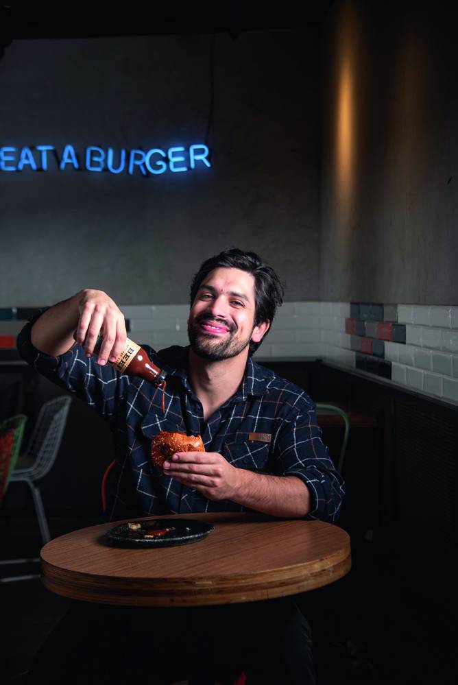 Beef Burger & Beer Homem sorrindo e segurando molho perto do lanche