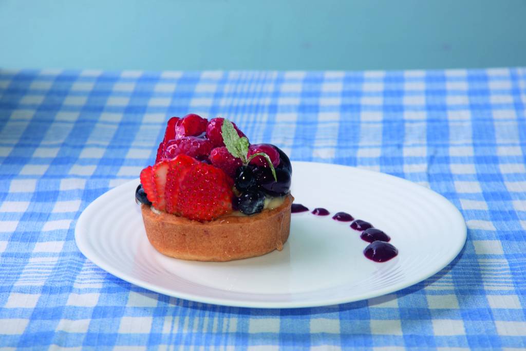 Brioche Brasil – torta de frutas vermelhas Torta com frutas em cima em cima de toalha quadriculada