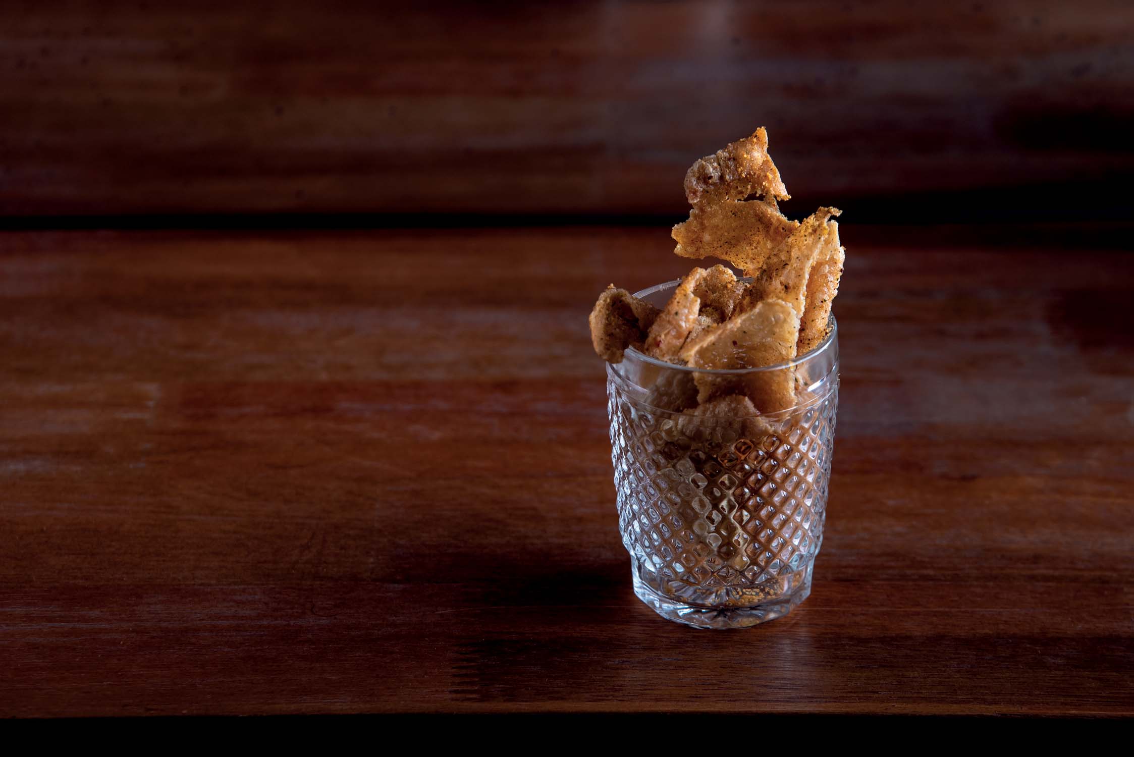 Porção de pele de frango fritas, com pimenta seca e limão