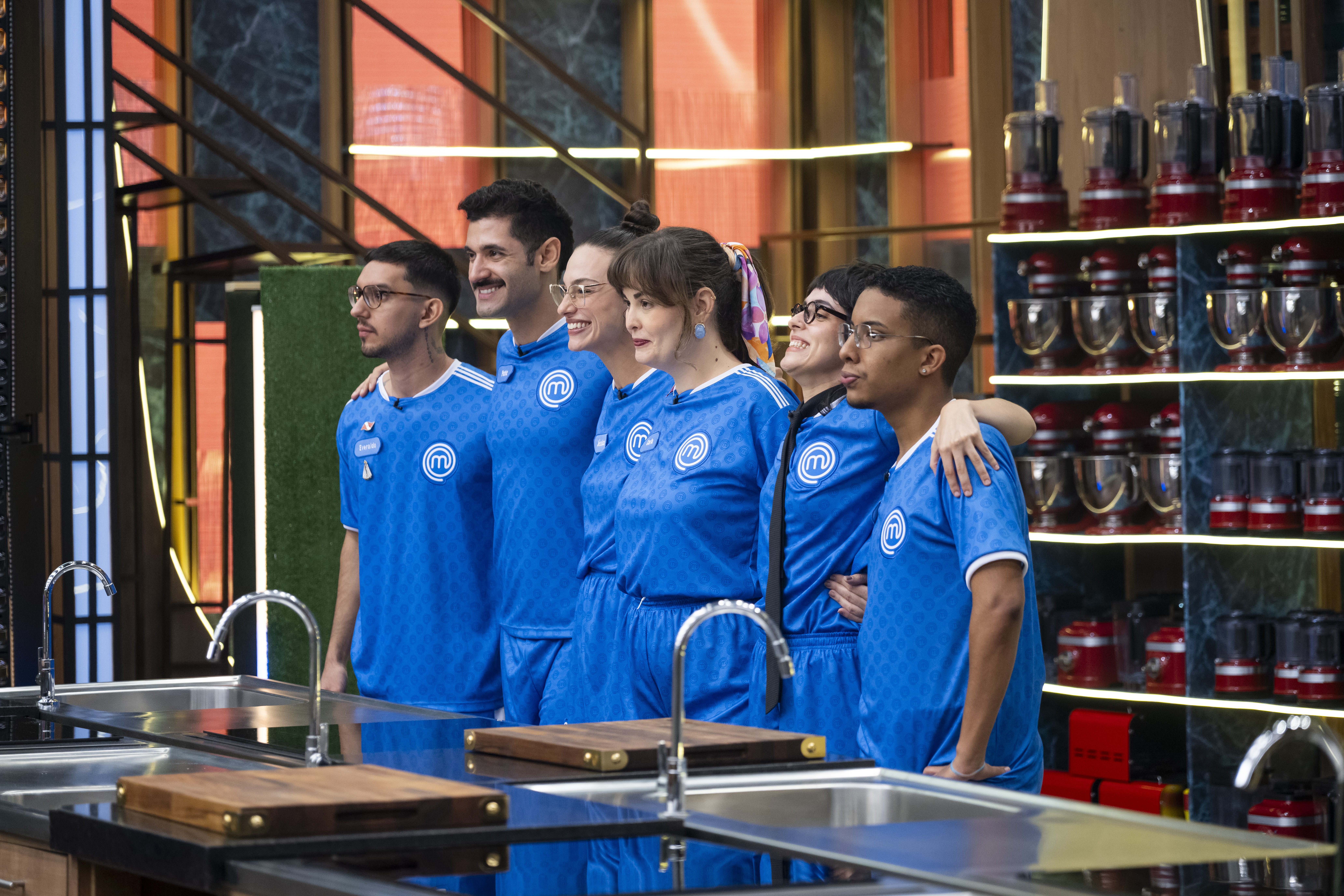 Seis pessoas, três homens e três mulheres, vestindo uniformes azuis com o logo 