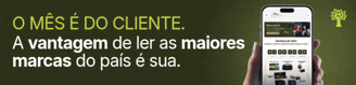 Mão segurando um smartphone com aplicativo de notícias exibindo O MÊS É DO CLIENTE. A vantagem de ler as maiores marcas do país é sua em fundo verde-escuro, com ícone de árvore no canto superior direito